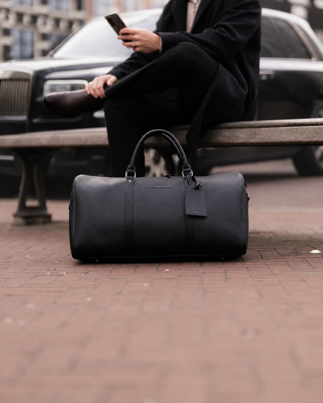 The Weekender in Black resting on a stone ledge